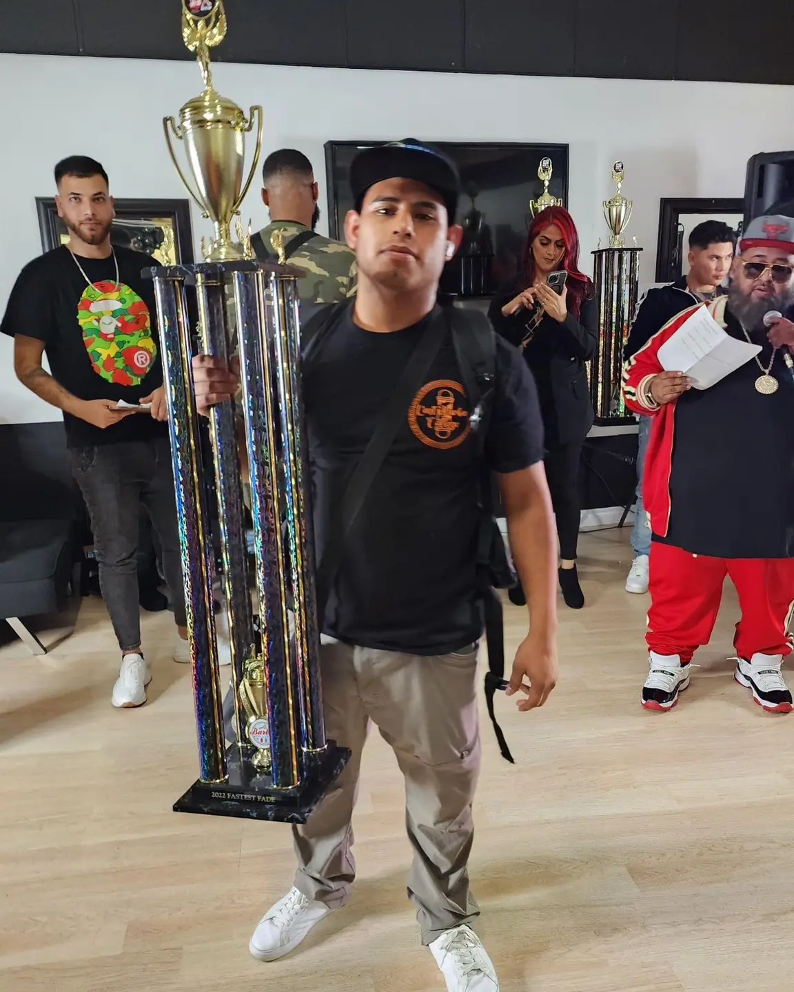 A man holding a large trophy with others in the background.