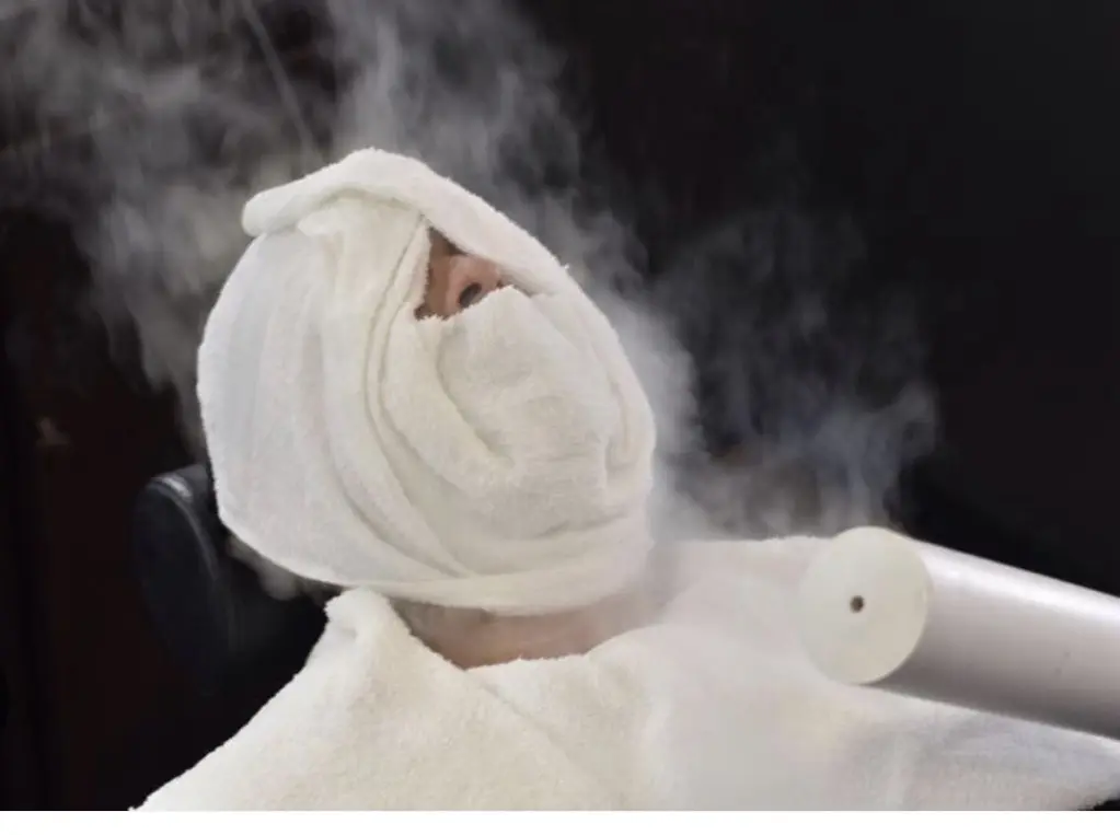 Person wrapped in a towel turban with steam around.