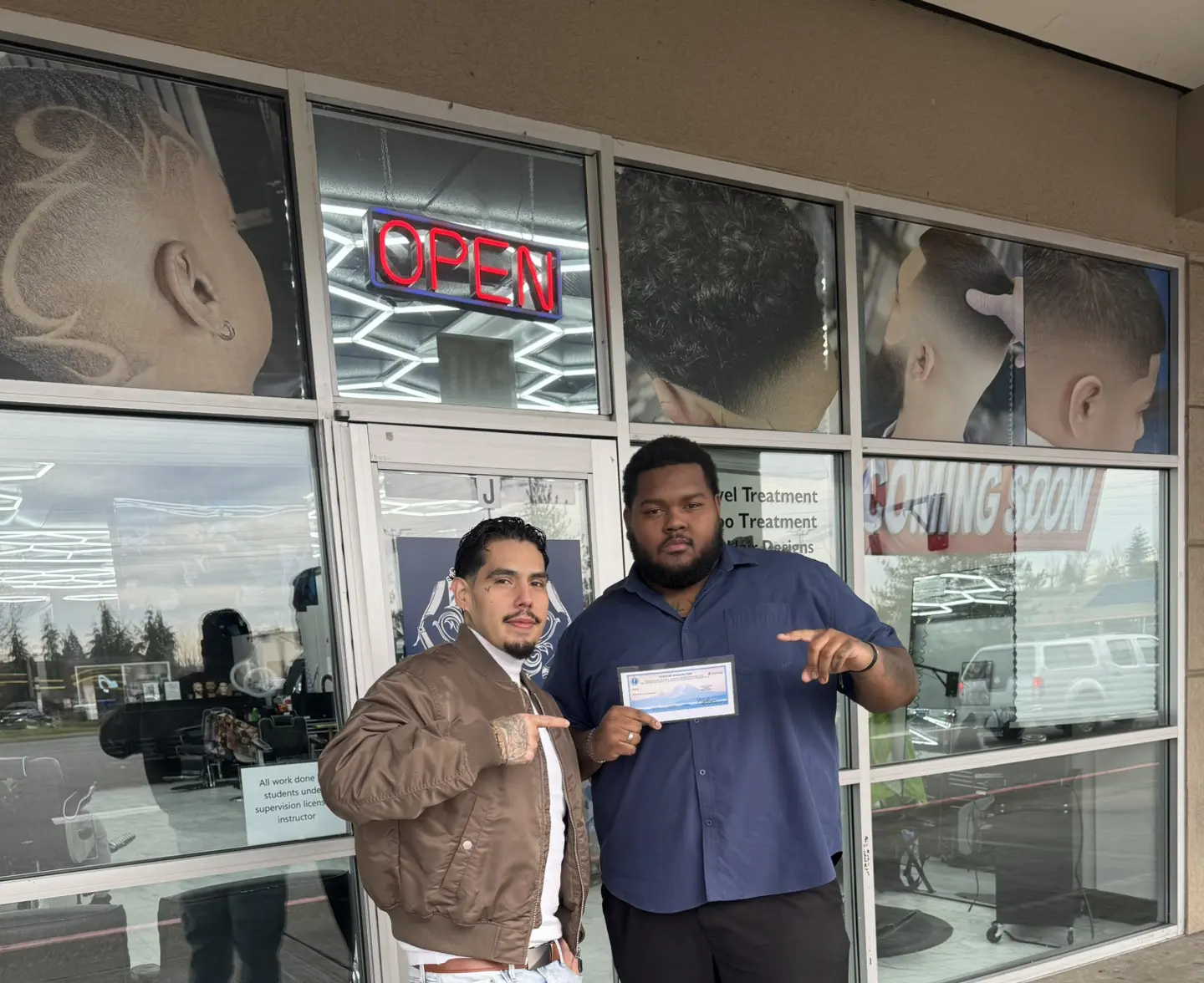Two men posing with a signed check in front of a glass window.