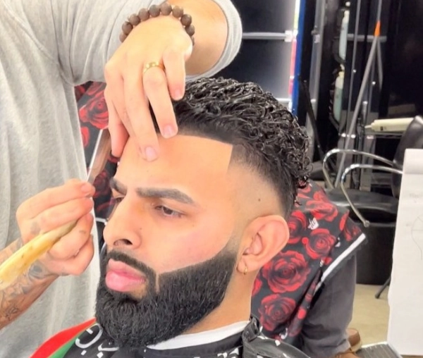 Barber giving a precise haircut and beard trim.